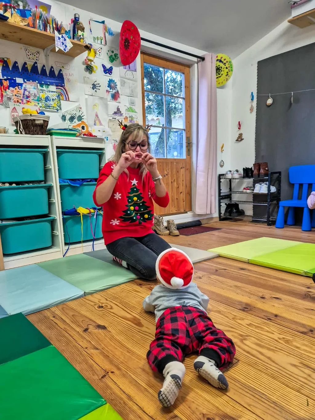 Atelier d'éveil de Noël : Jenn en pull à sapin et bébé en bonnet rouge