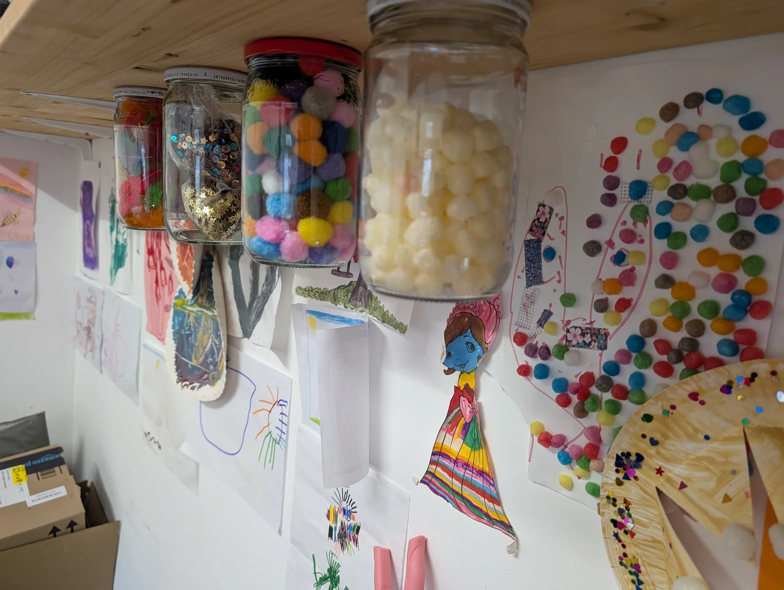 Mur de bocaux de pompons et créations d'enfants exposées