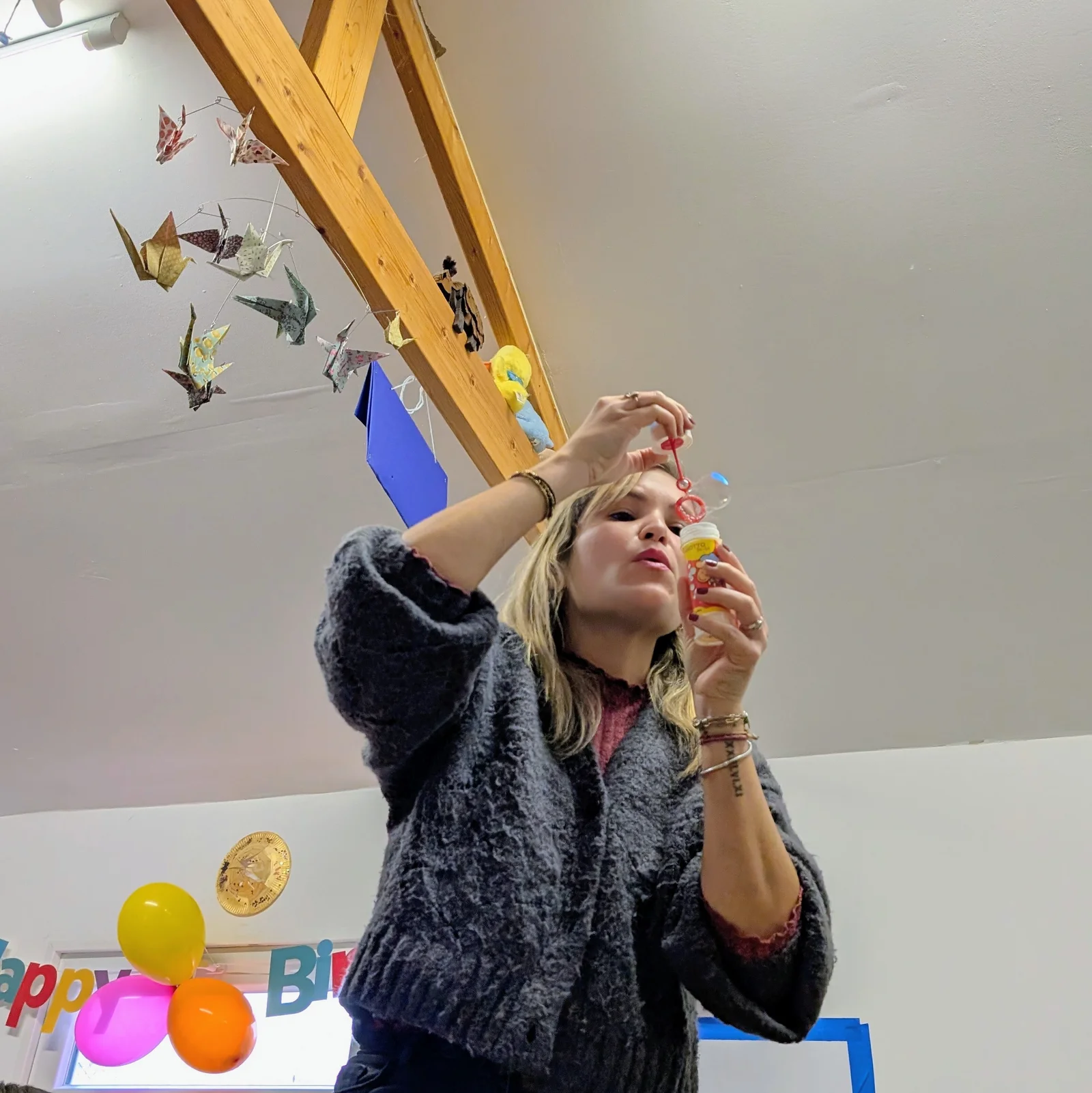 Jenn soufflant des bulles de savon sous une guirlande d'origamis